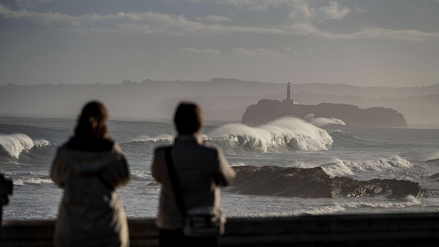 Dos mujeres hacen fotos con la Isla de Mouro al fondo, en la bahía de Santander, este lunes