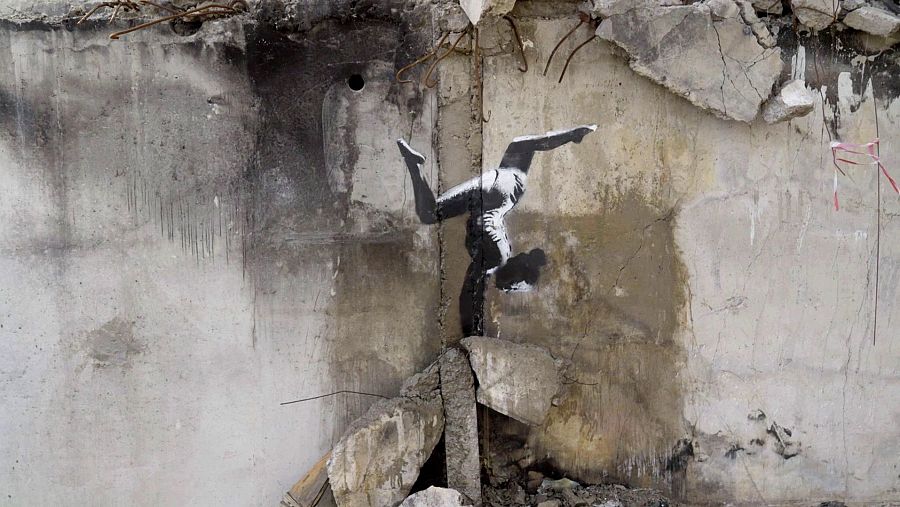 Grafiti de una gimnasta negra en equilibrio sobre escombros, en un muro agrietado.  Técnica de estarcido.  Imagen de resistencia y esperanza.