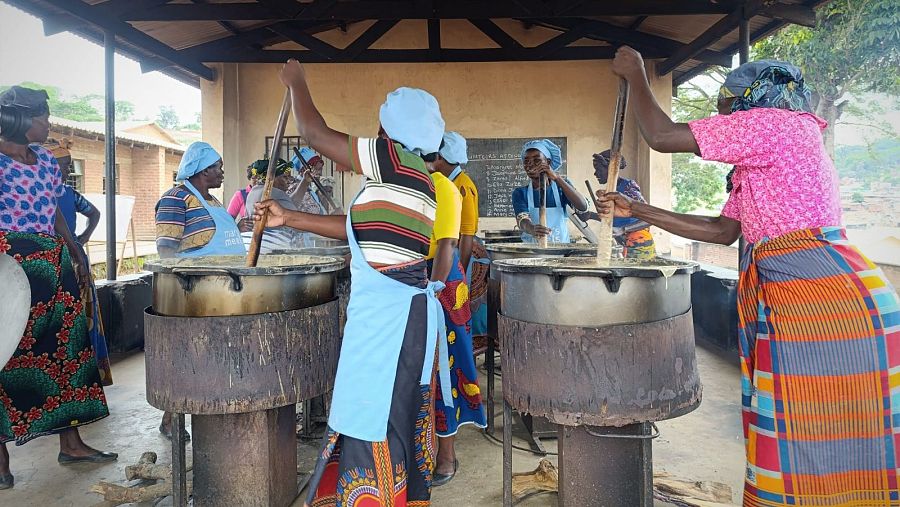 Varias mujeres cocinan comida para repartir en las colas del hambre
