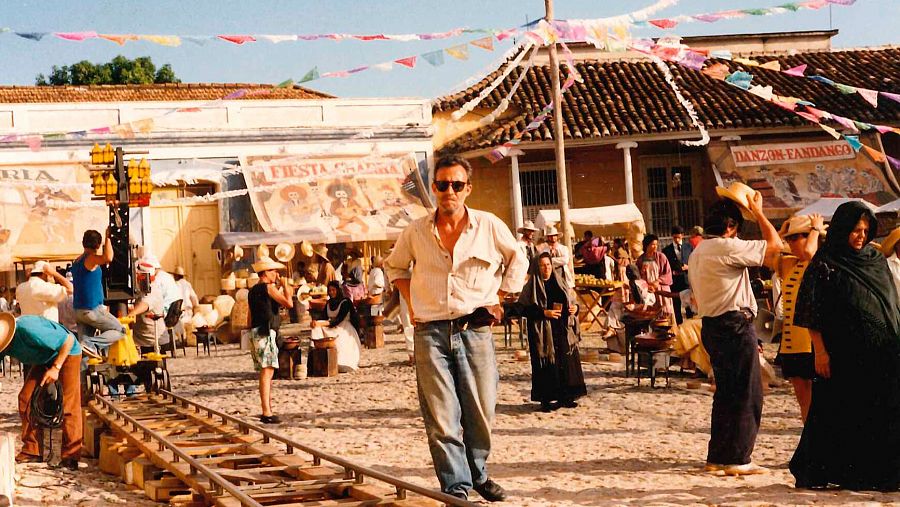 Félix Murcia, director de arte, en el rodaje de una película ambientada en una plaza festiva con vías de tren, extras con vestuario de época y carteles que anuncian 