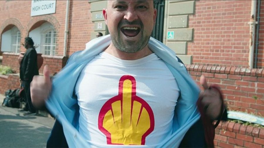 Manifestante con camiseta modificada protesta frente al Tribunal Superior. Gesto obsceno parodia logo Shell.  Posible conflicto legal.