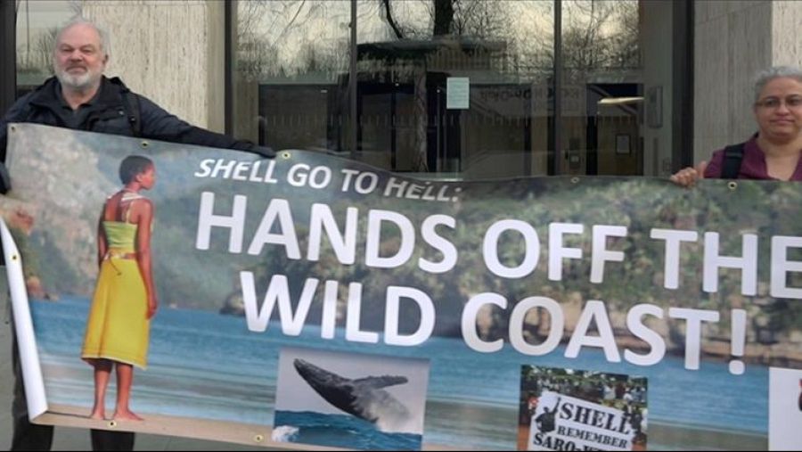 Protesta contra Shell con pancarta exigiendo que se retiren de la costa salvaje, incluyendo imágenes de una playa, una ballena y una alusión a un sabotaje.