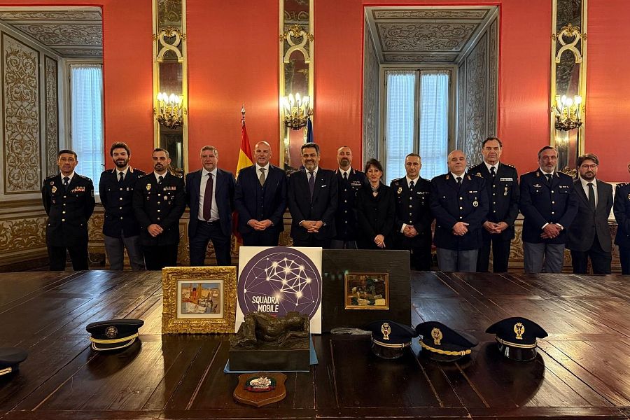 Entrega oficial de tres obras de arte recuperadas: dos pinturas y una escultura.  Participan autoridades españolas e italianas, en una sala con banderas de ambos países.