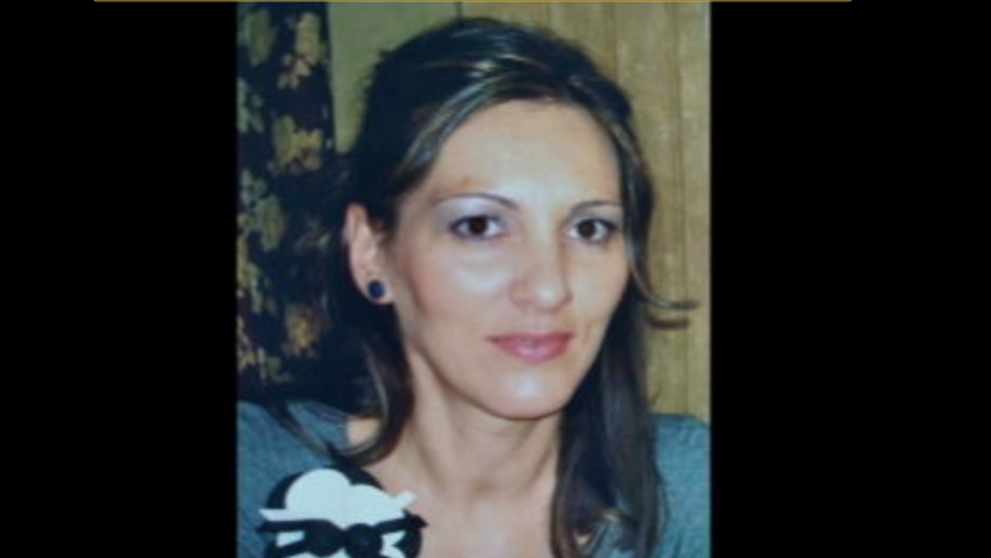 Retrato de mujer con pelo castaño recogido, blusa gris oscura y broche blanco con detalle negro.  Campaña de concienciación sobre violencia de género.