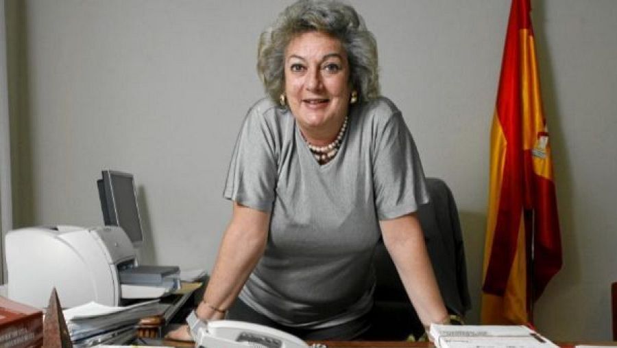 Soledad Cazorla, en su despacho, trabajando.  Se observa una bandera española y el texto 