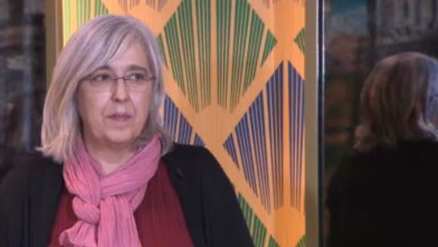 Mujer con gafas y bufanda rosa, blusa granate.  Texto: Objetivo Igualdad.