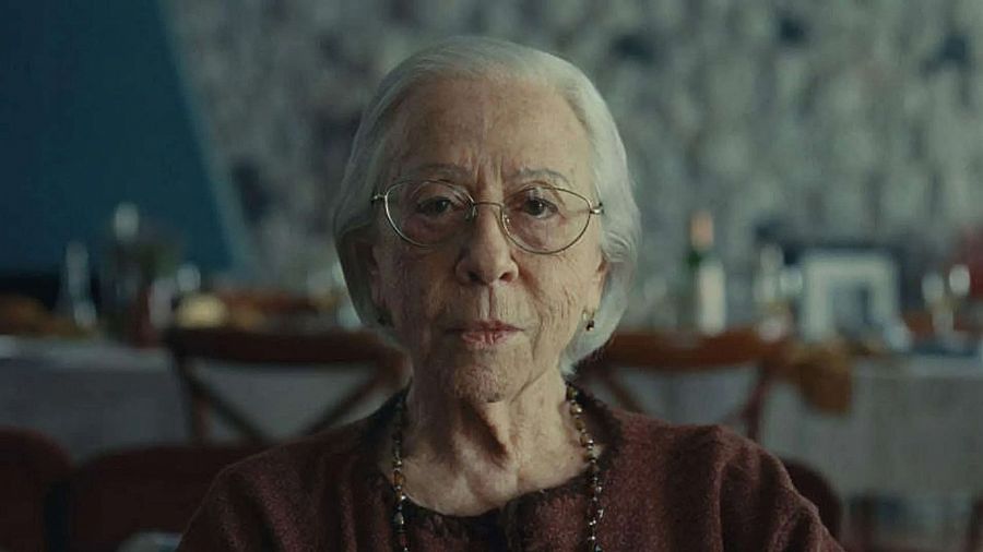 Fernanda Montenegro, actriz brasileña, con pelo corto blanco y gafas, viste blusa granate y mira directamente a la cámara con expresión seria.