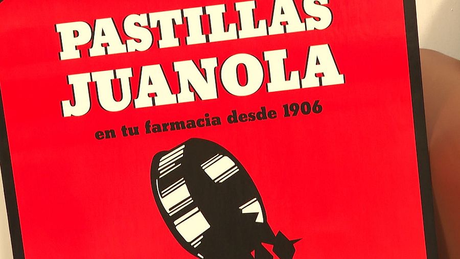 Anuncio de Pastillas Juanola con fondo rojo, texto blanco y la imagen de una pastilla.  Se menciona su presencia en farmacias desde 1906.