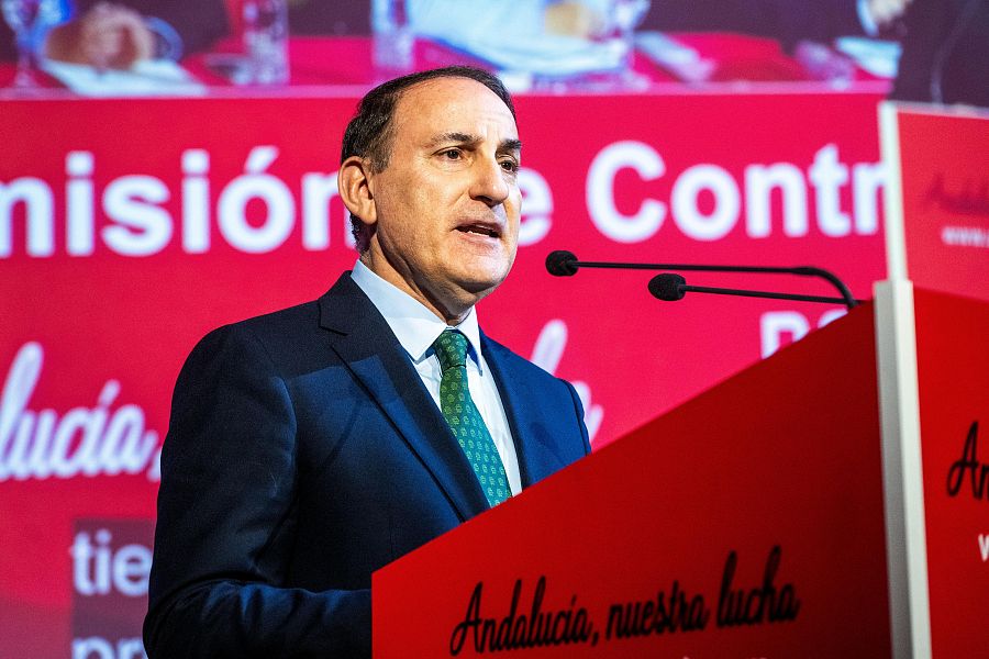 Discurso de un hombre en traje azul marino y corbata verde, desde un atril rojo con la frase 