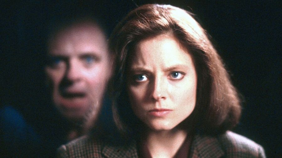 Primer plano de Jodie Foster con expresión de miedo; fondo desenfocado con un rostro gritando.  Atmósfera de suspense.