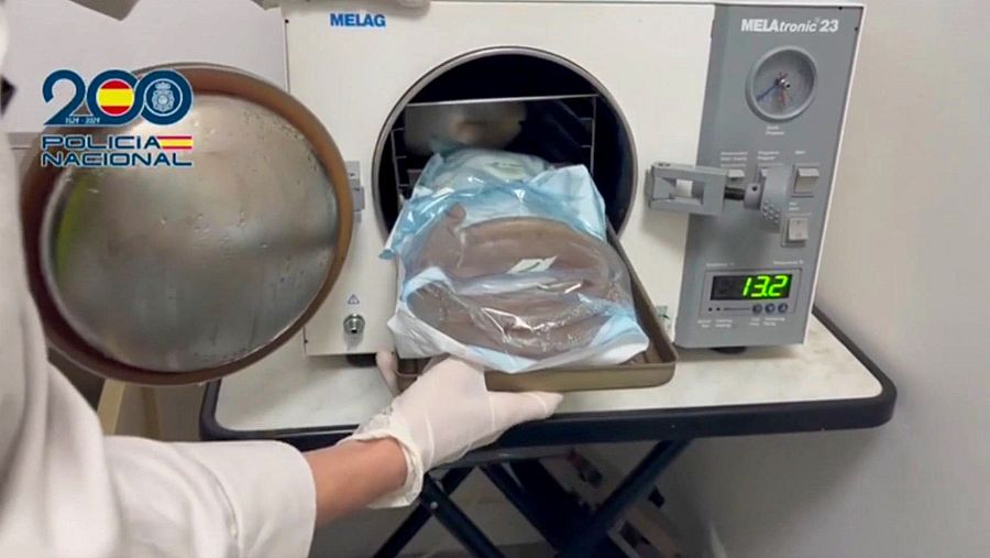 Autoclave MELAG mostrando 132°C, con instrumental médico esterilizado y una persona con bata blanca retirando una bandeja.