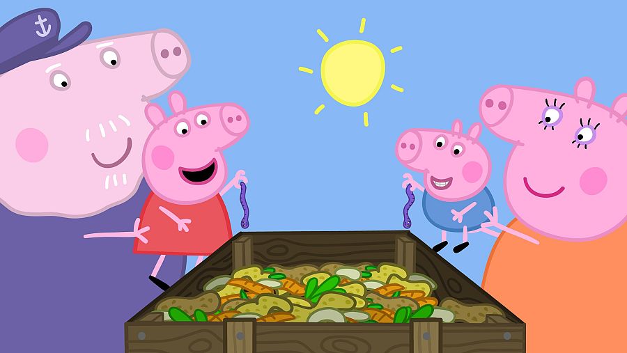 La familia Pig composta, con Peppa y George añadiendo lombrices a un contenedor de madera lleno de restos vegetales.  Abuelo Pig observa sonriente.