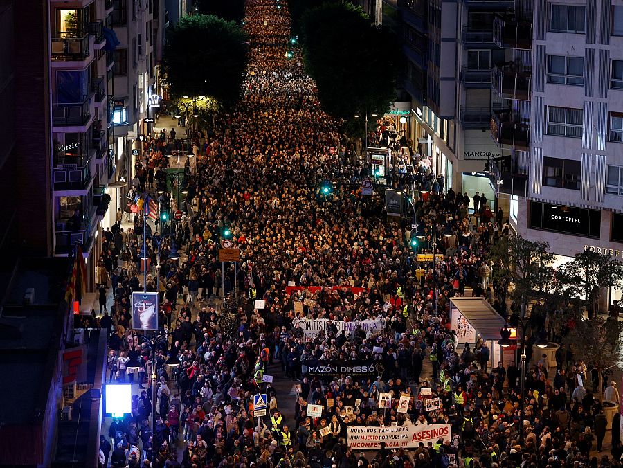 Manifestación nocturna en Valencia vista desde arriba. Multitud con pancartas y lemas visibles como 