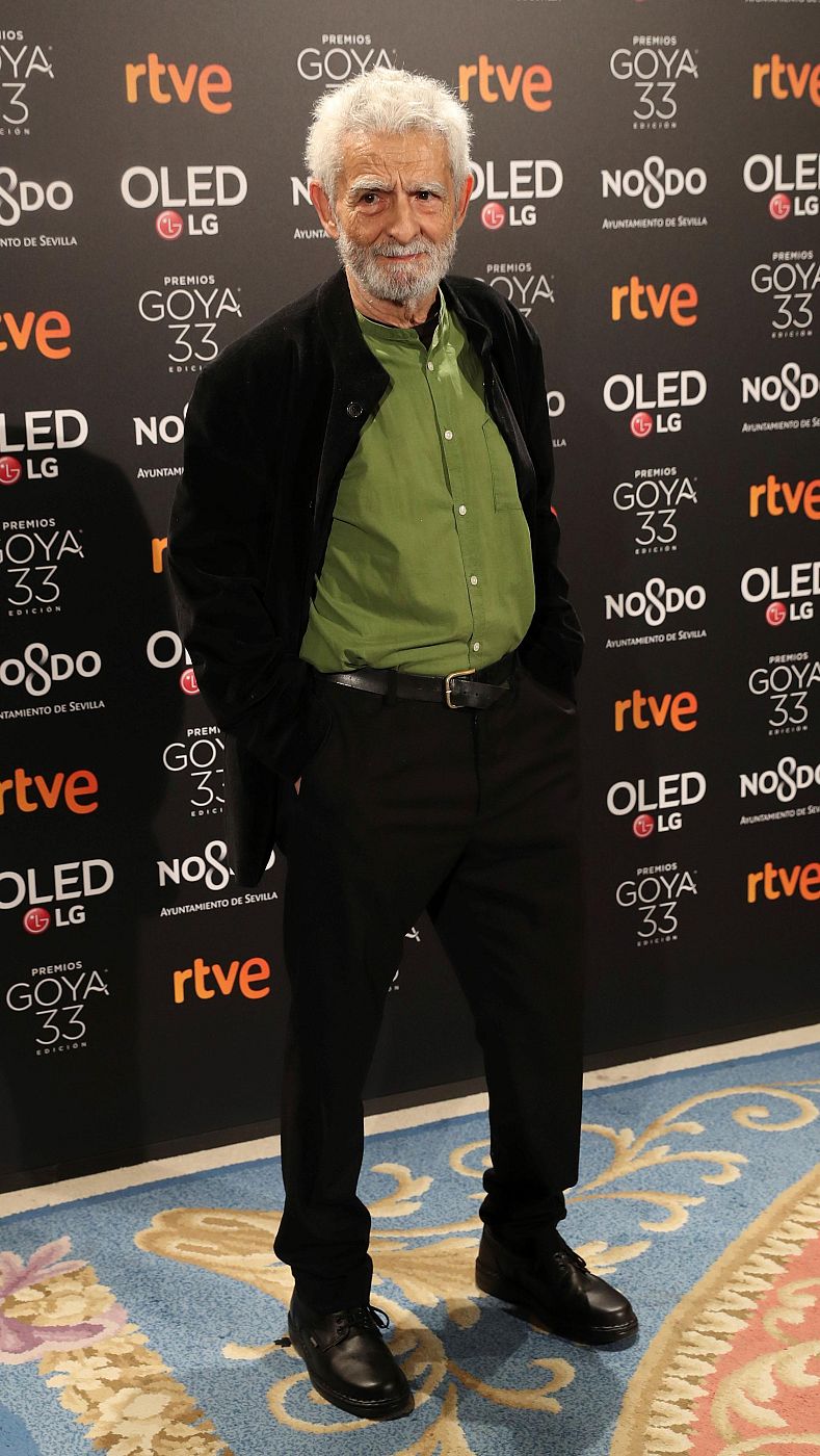 Juan Margallo en photocall de los Premios Goya 33. Camisa verde oliva, pantalones negros. Fondo con logotipos de patrocinadores.