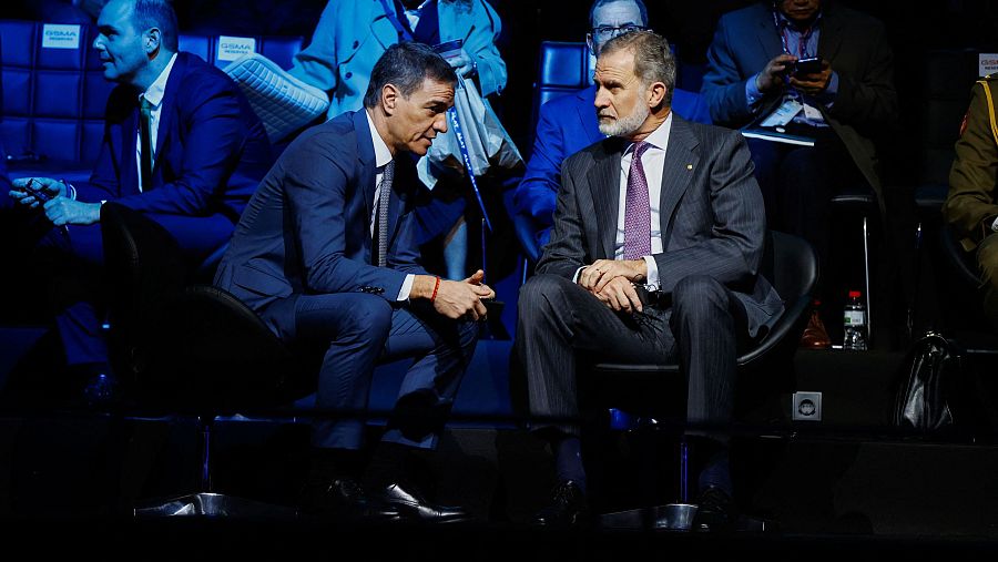 El Rey Felipe VI y Pedro Sánchez, en conversación durante el Mobile World Congress.  Visten trajes oscuros y están sentados en un auditorio.