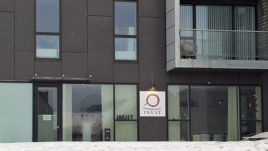 Edificio moderno con fachada oscura y ventanas rectangulares.  Letrero iluminado con la palabra 