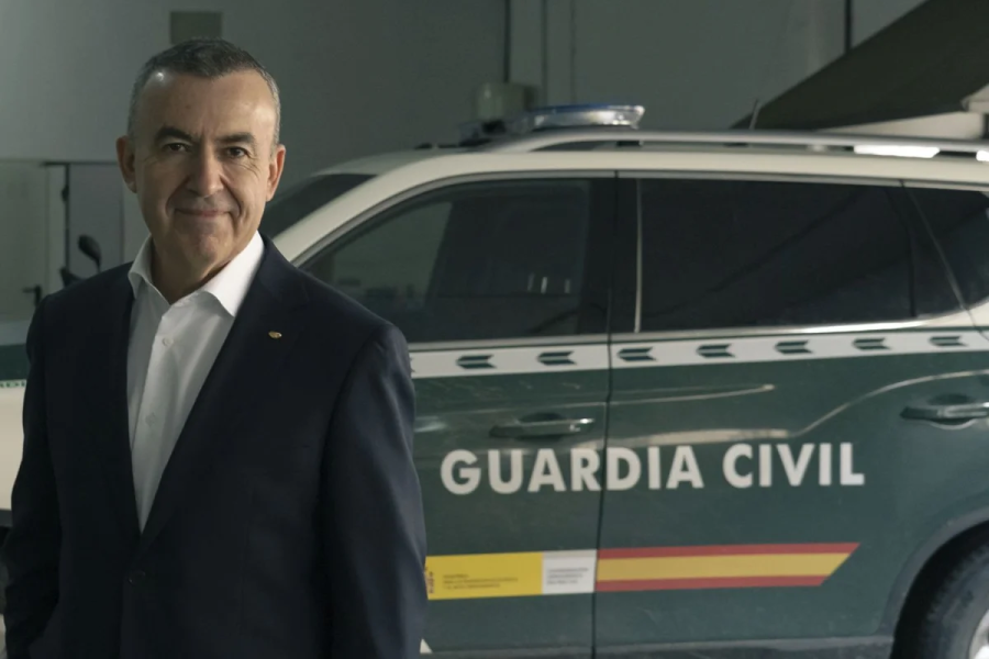 Lorenzo Silva, de mediana edad y pelo canoso, sonríe ligeramente en una foto tomada en un cuartel de la Guardia Civil, junto a un vehículo oficial.