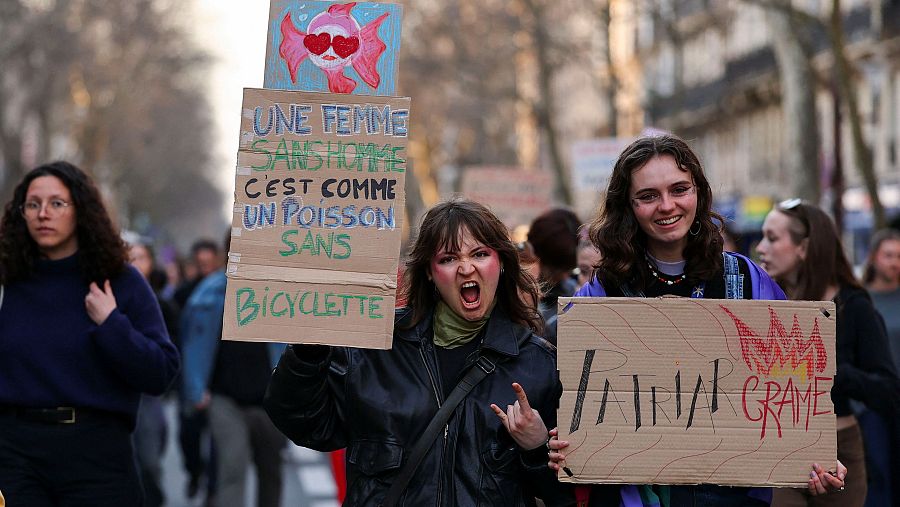 Dos mujeres posan mientras enseñan las pancartas en las que lanzan mensajes feministas escritos en francés.