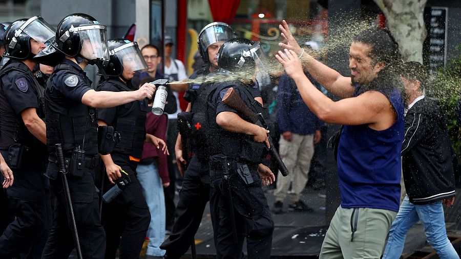 Un agente de policía usa un aerosol antidisturbios contra un manifestante