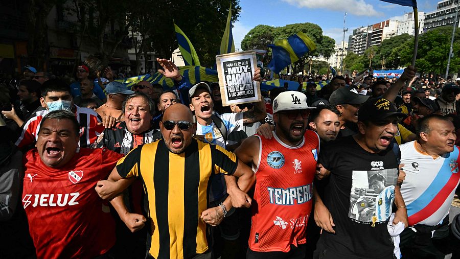 Manifestantes gritan consignas durante una protesta de jubilados, apoyados por hinchas de fútbol