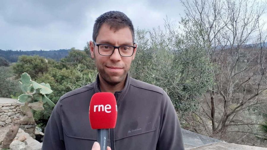 Entrevista a Jordi Benages con un micrófono de RNE. Lleva gafas y chaqueta oscura. Fondo rural.