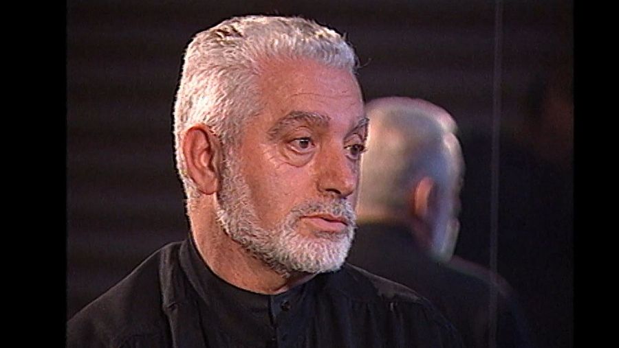 Imagen de Paco Rabanne, de edad avanzada, con pelo y barba canos, vistiendo camisa oscura, en un fotograma de un documental.