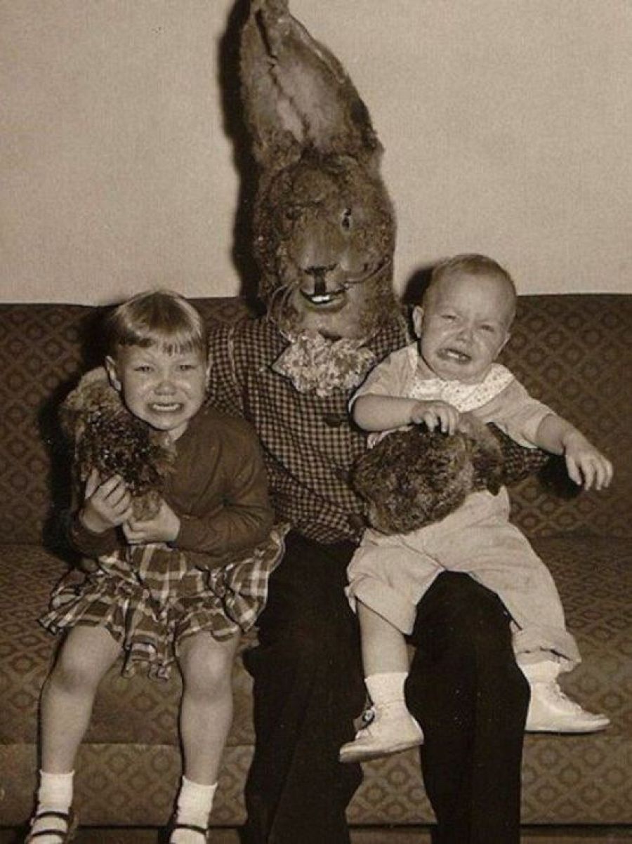 Foto en blanco y negro (1955): dos niños, uno sonriente y otro llorando, junto a un adulto con un disfraz de conejo aparentemente casero.