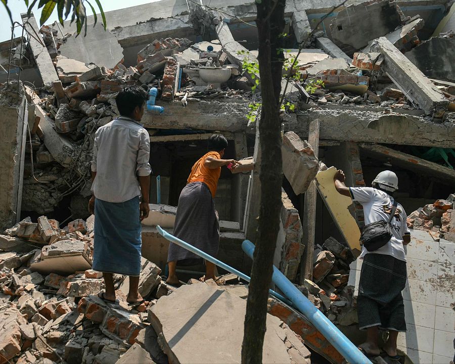 Varias personas buscan supervivientes entre los escombros de un edificio destruido en Mandalay