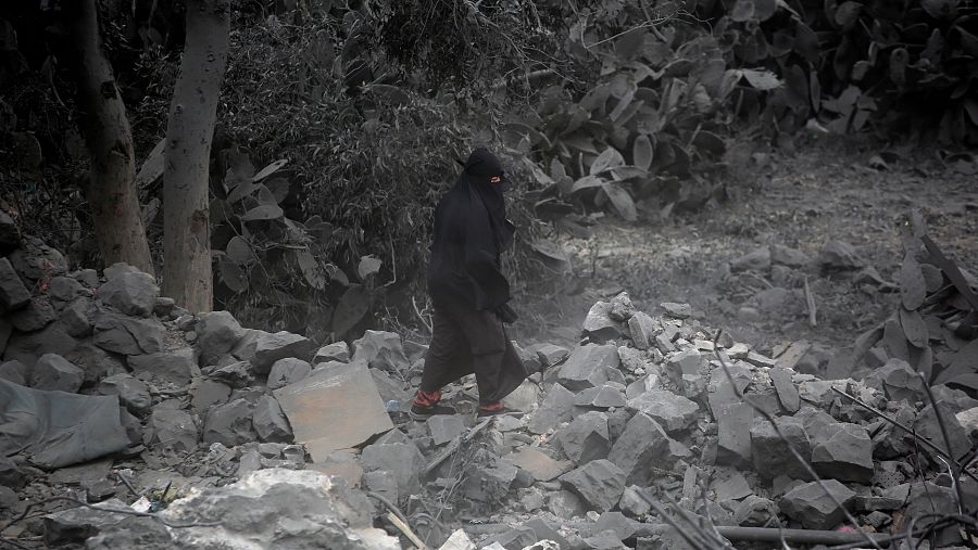 Una mujer inspecciona los daños alrededor de un edificio después de los ataques aéreos estadounidenses en Saná, Yemen.
