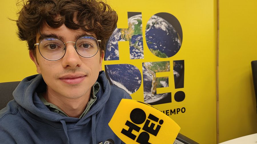 Entrevista a Melerus en el podcast HOPE!, con fondo amarillo y logo del podcast incluyendo una imagen de la Tierra. Lleva gafas y sudadera azul.