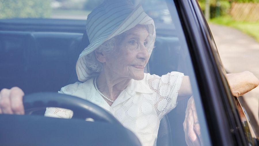 Una persona mayor disfruta de la conducción de un automóvil