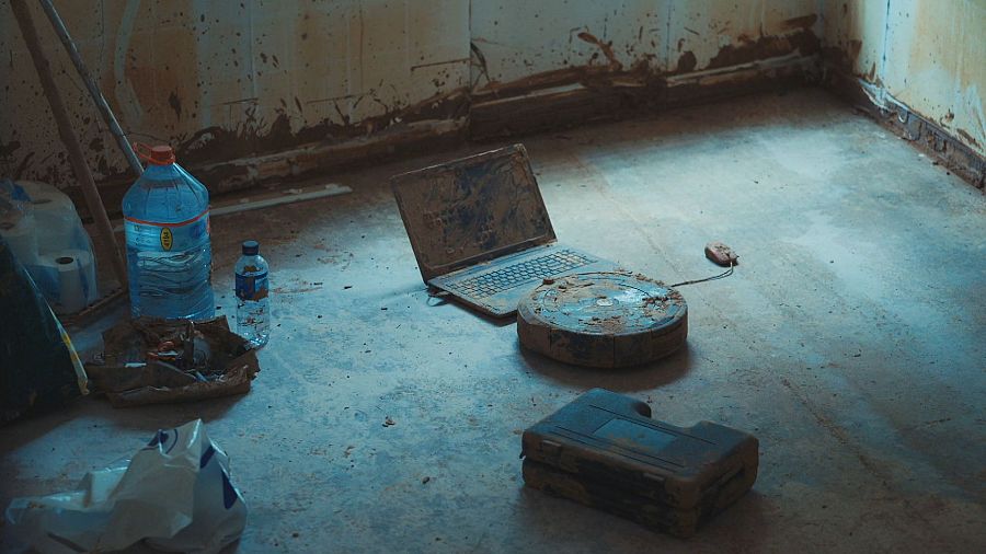 Barro seco cubre el suelo y diversos objetos, incluyendo un ordenador portátil y una báscula, tras una riada.