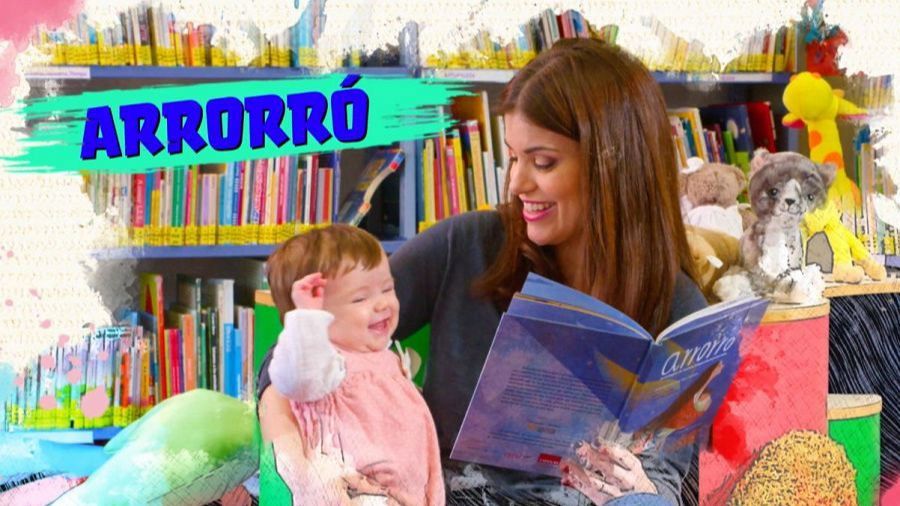 Mujer leyendo cuento infantil a bebé en biblioteca, promoviendo la lectura en el marco de una campaña.  Se observa el título 