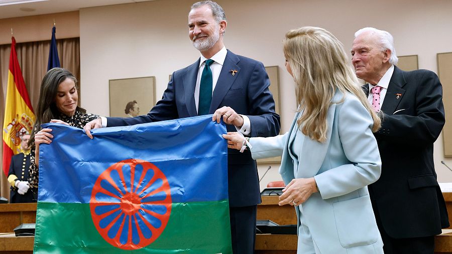 El rey Felipe VI y la reina Letizia reciben una bandera gitana tras presidir el acto de conmemoración en el Congreso de los Diputados.
