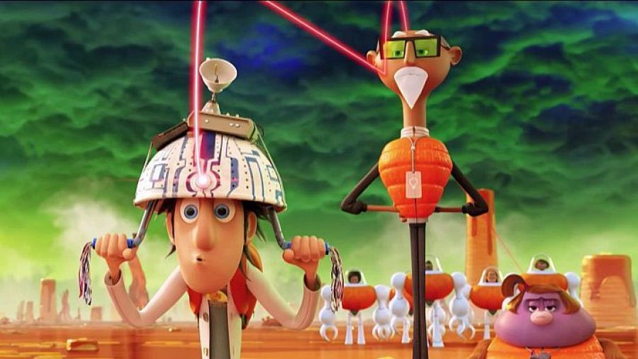 Fotograma de animación mostrando a Flint Lockwood con un casco y cables, junto a un personaje con gafas y chaleco naranja que recibe rayos láser en los ojos. Fondo desértico con otros personajes.