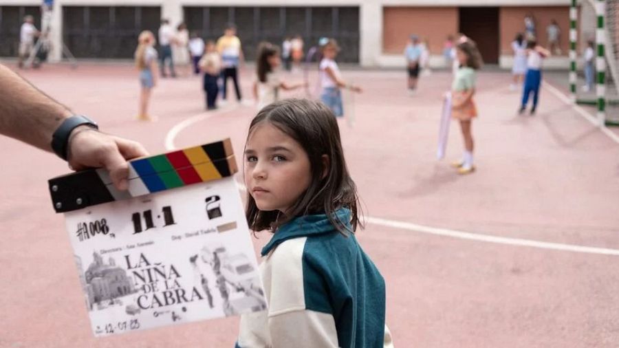 Rodaje de película infantil. Niña con chaqueta bicolor mira a cámara. Claqueta indica escena 11.1, 12 de julio de 2023.