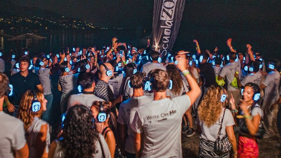 Fiesta silenciosa nocturna: multitud bailando con auriculares inalámbricos. Algunos asistentes llevan camisetas con la frase 