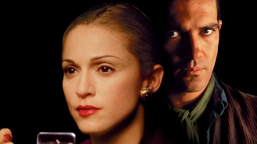 Imagen promocional de 'Evita' con Madonna (Eva Perón) y Antonio Banderas (Che).  Ella, con el pelo recogido y labios rojos, mira directamente a cámara; él viste camisa y chaqueta oscura. Iluminación tenue.