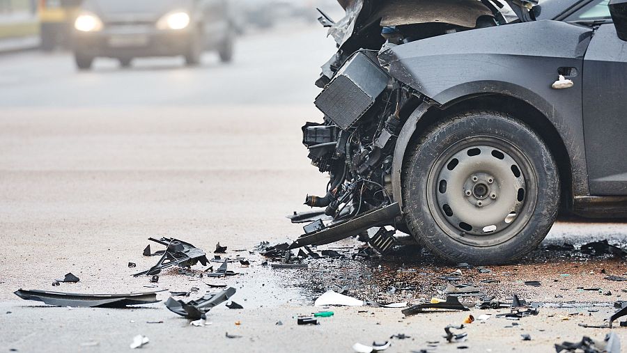 Trozos de carrocería de un vehículo accidentado, reposan sobre el asfalto.