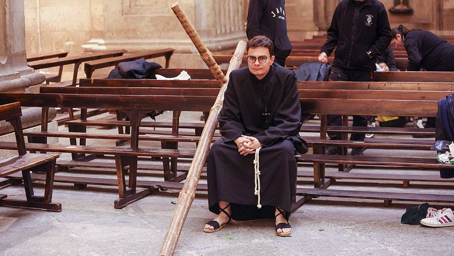 Cofrade esperando a salir en procesión con una cruz penitencial en Salamanca.