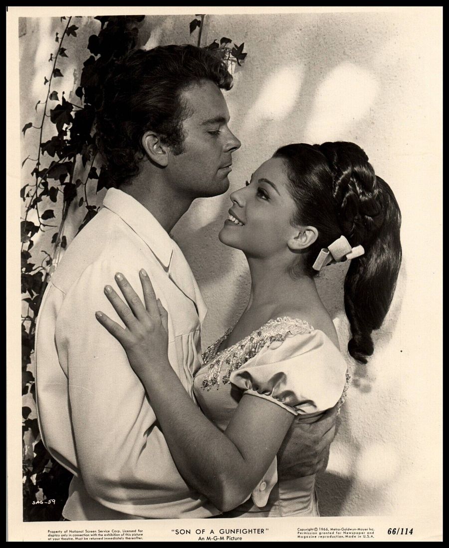 Imagen en blanco y negro: Russ Tamblyn y María Granada, abrazados, en una escena romántica de la película 