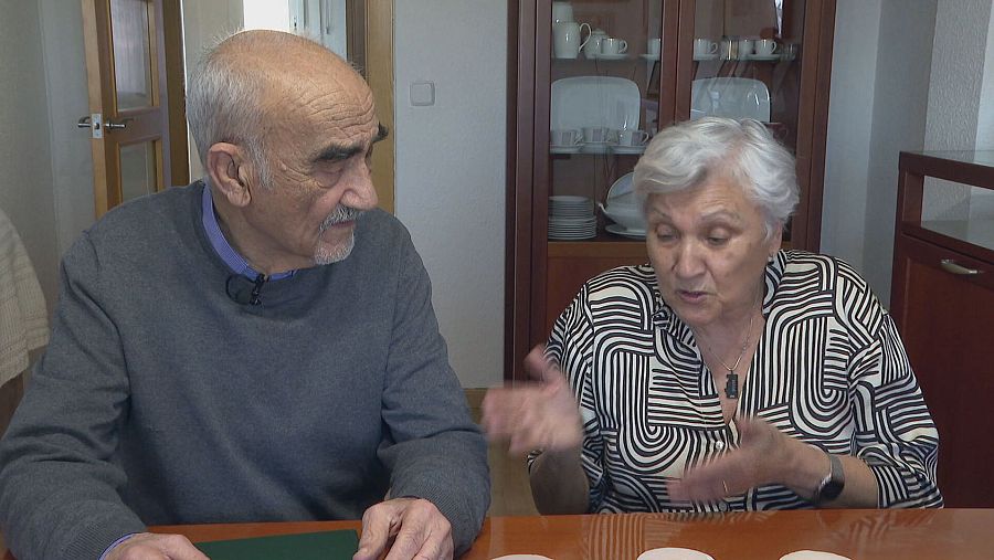 Entrevista a dos personas: él con jersey gris y micrófono, ella con blusa a rayas, gesticulando activamente.