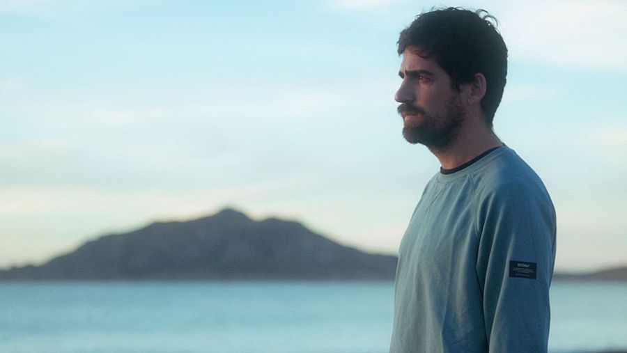 Hombre contemplativo en paisaje costero al atardecer. Promoción del capítulo 1 de la serie 