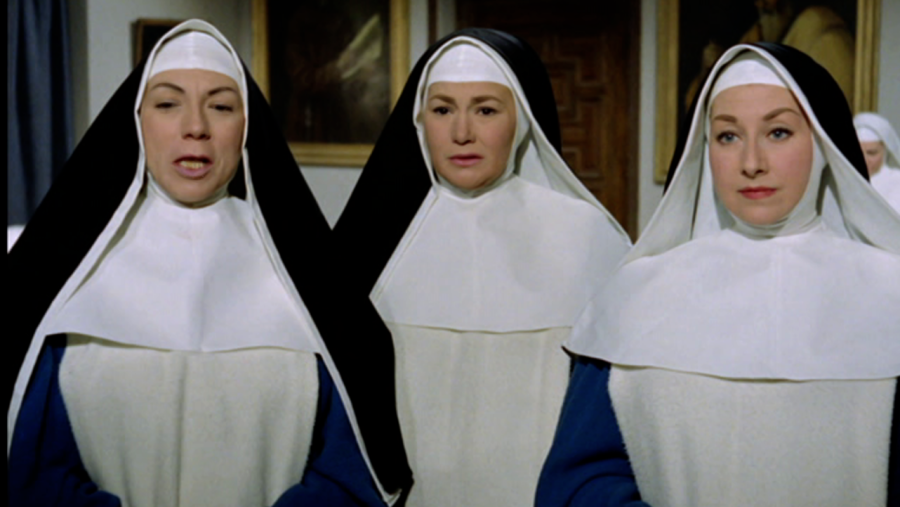 Escena de interior con tres monjas en hábito, una de ellas con la boca entreabierta, en un ambiente que sugiere un espacio religioso.