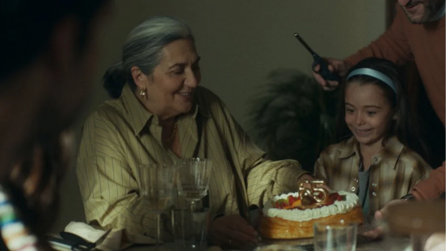 Celebración familiar con tarta de cumpleaños (velas: 55). Una mujer mayor y una niña. Ambiente festivo.