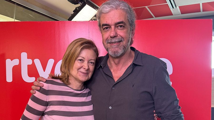 Presentadores o invitados de un programa cultural de RTVE posan juntos ante un fondo rojo con el logo de la cadena. Mujer con camiseta de rayas, hombre con camisa oscura.