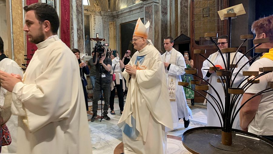Llegada de Erdő con el hábito de obispo, con una persona cargando el birrete de cardenal detrás