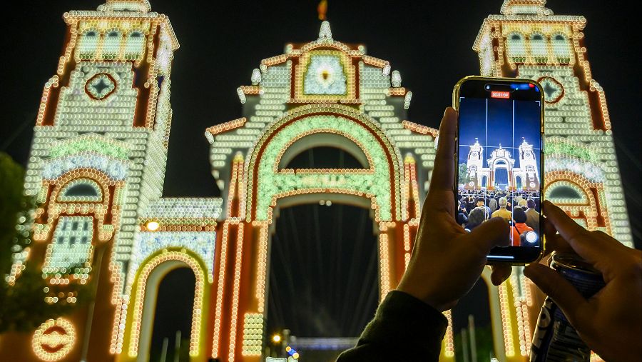Una persona fotografía la portada de la Feria de Abril de Sevilla 2025