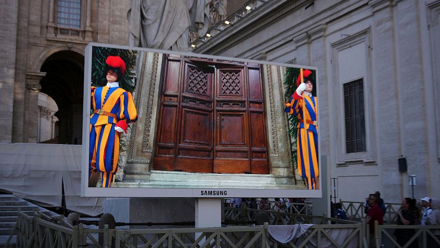 La Guardia Suiza de pie mientras se cierra la puerta de la Capilla Sixtina