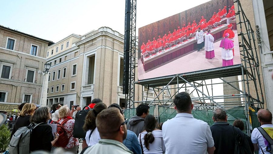 Fieles observan una pantalla gigante que muestra imágenes de los cardenales electores